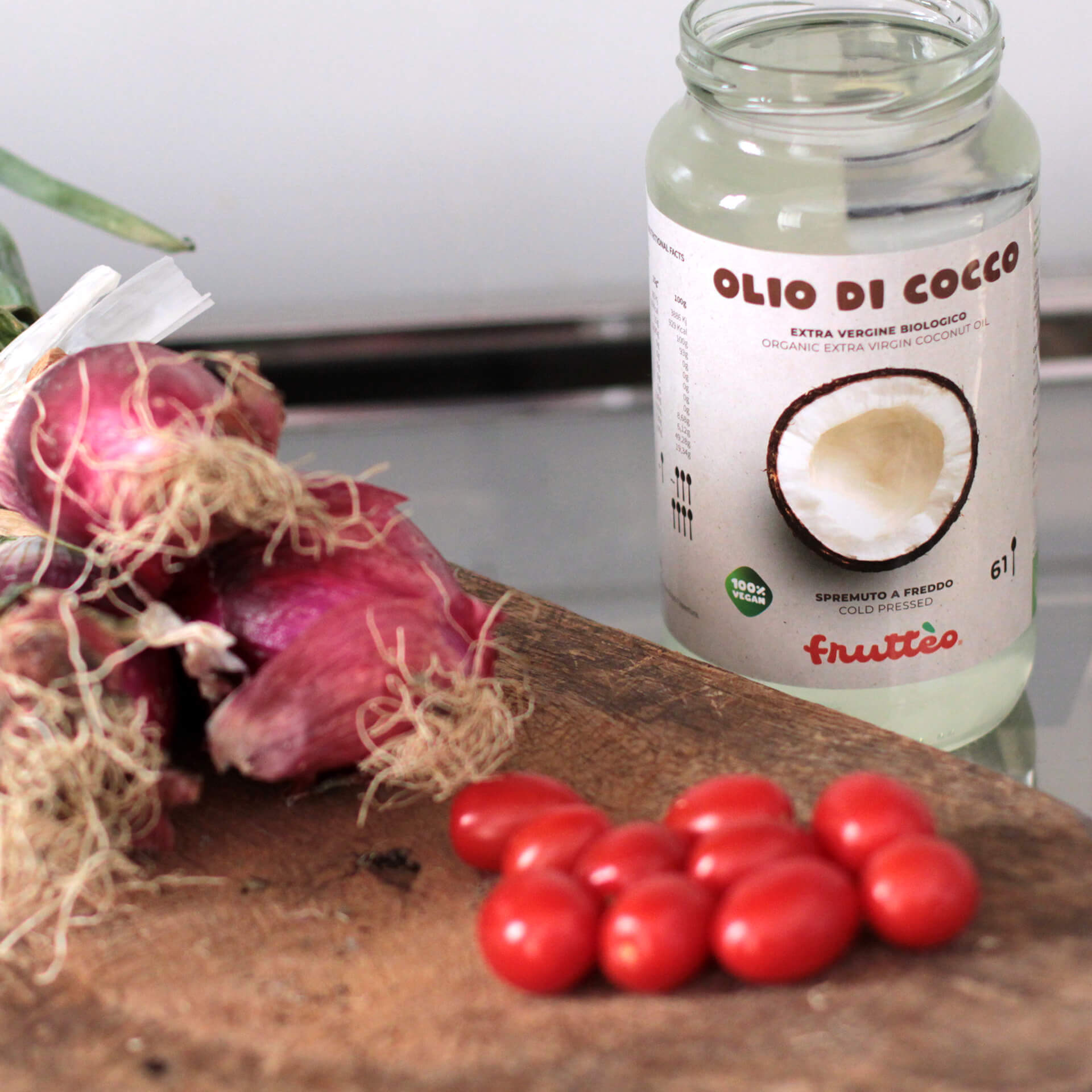 Barattolo Olio di Cocco Frutteo da 1000 (mille) millilitri aperto - con accanto pomodori e cipolle su tagliere. 100% Vegan Friendly
